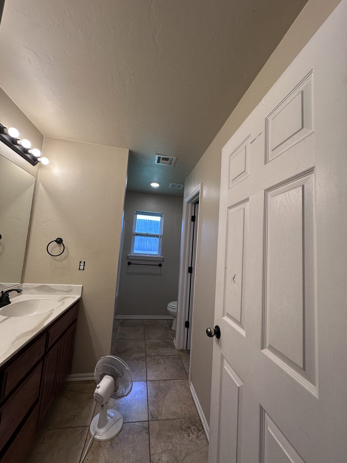 Hallway of new white cabinetry with recessed lighting and tile flooring in a finished remodel